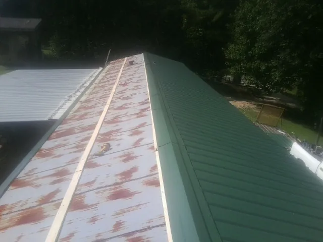 Old rusted panels beside newly installed green metal roofing — Wind Damage Roof Repair by Roofing Brothers in Genesee Depot