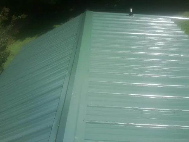 New green metal panels meeting at the ridge of a roof — Flat Roof Repair work by our crew in Genesee Depot