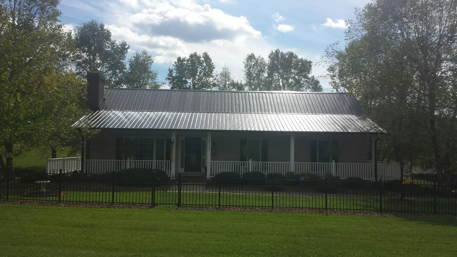 Gray metal roof on a brick ranch with a full width front porch — Gutter Guard Installation work by our crew in Genesee Depot