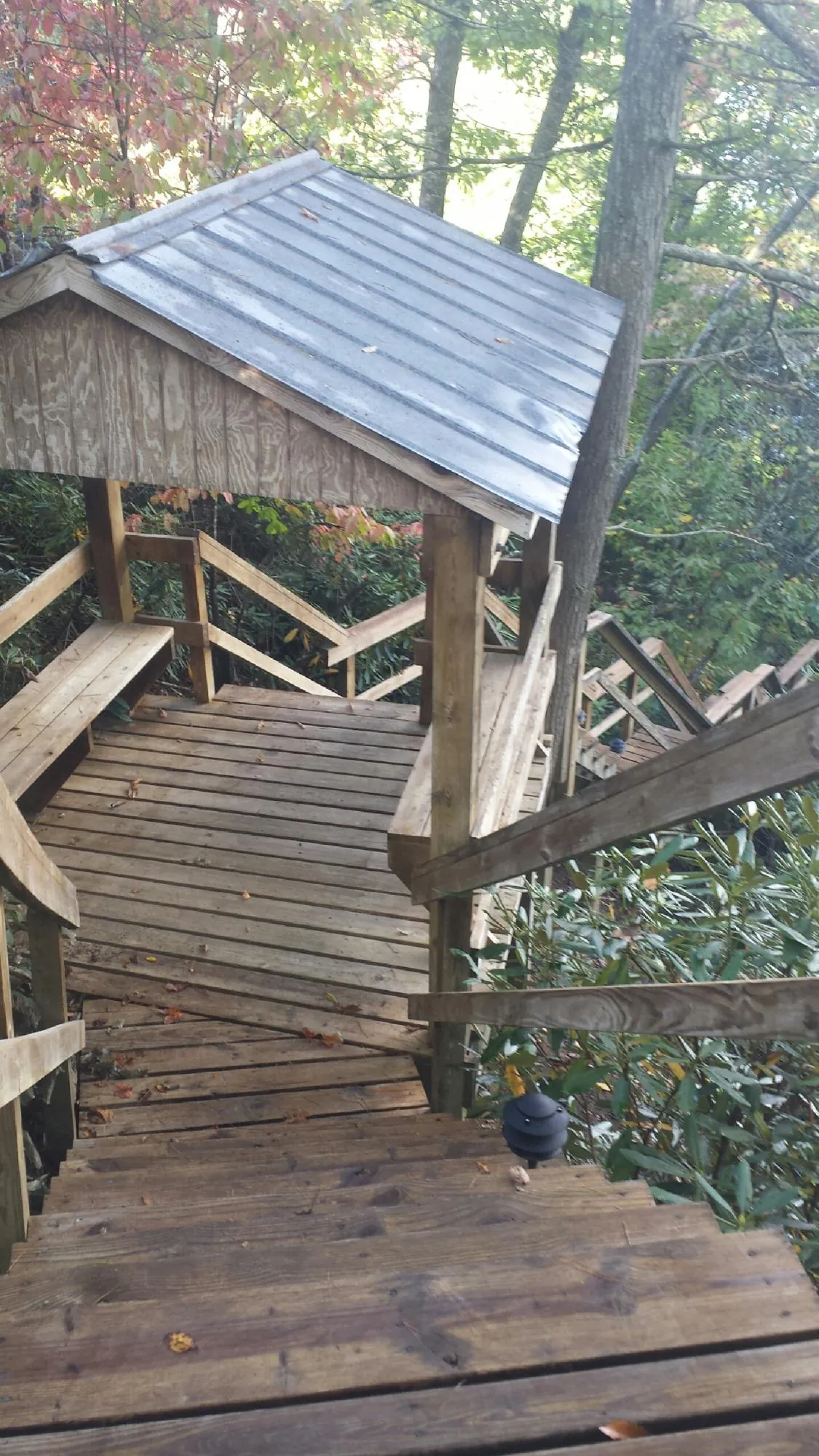 Metal roofed shelter over wooden steps on a wooded walkway — Skylight Repair & Installation work by our crew in Genesee Depot