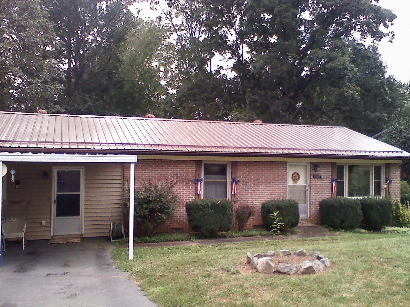 Bronze metal roof and carport on a brick ranch home — Roof Repair work by our crew in Genesee Depot