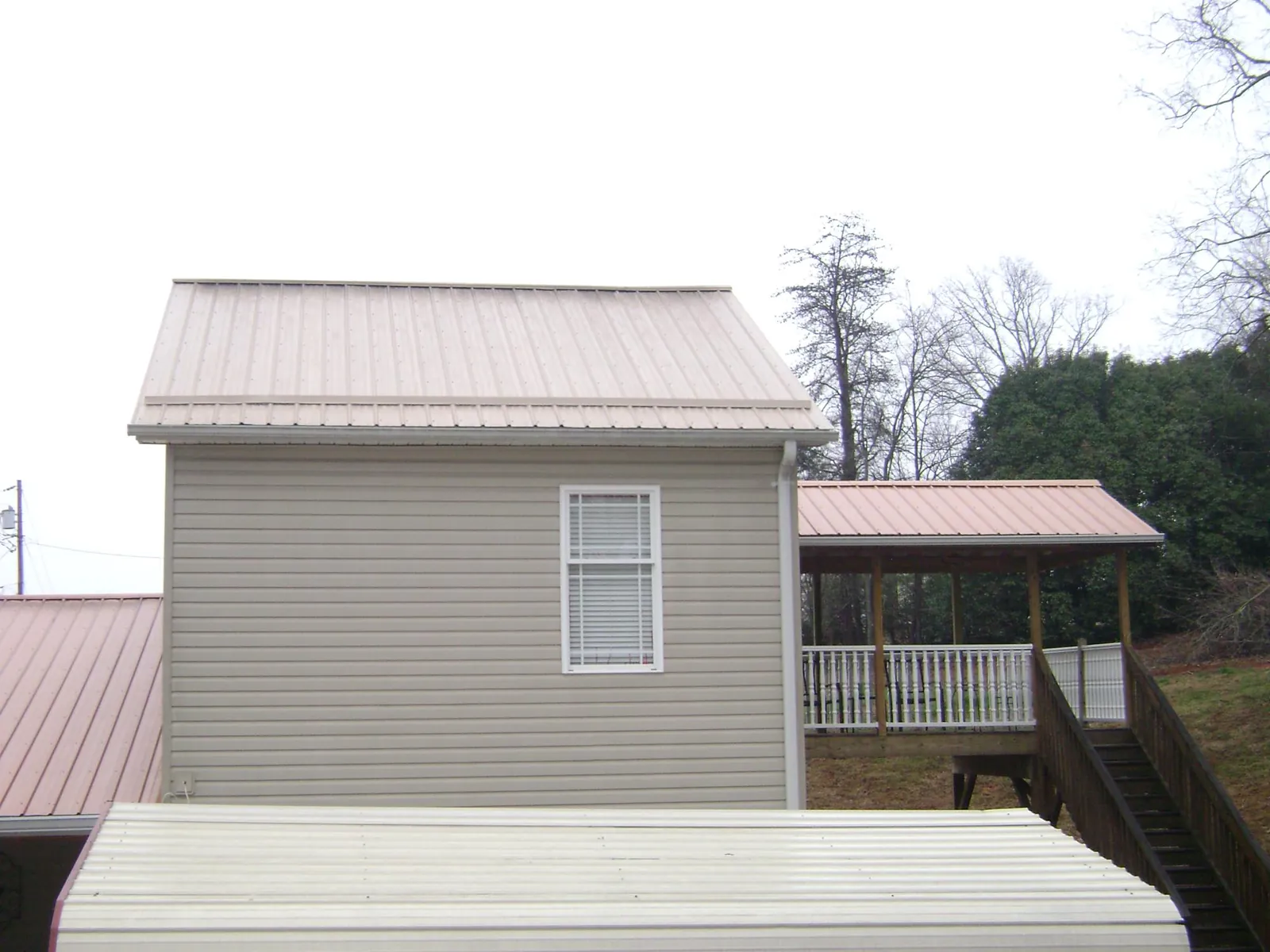 Tan metal roofs on a two story addition and attached porch, from a Roof Replacement job in Genesee Depot