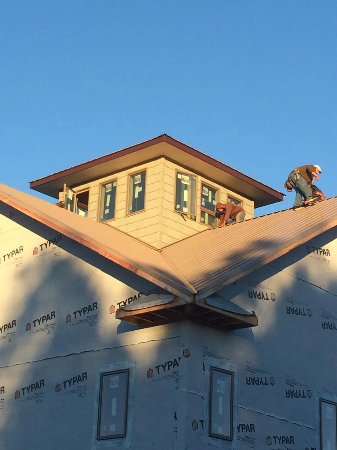 Roofers working around a rooftop cupola on a new metal roof at sunset — Roof Waterproofing in Genesee Depot by Roofing Brothers